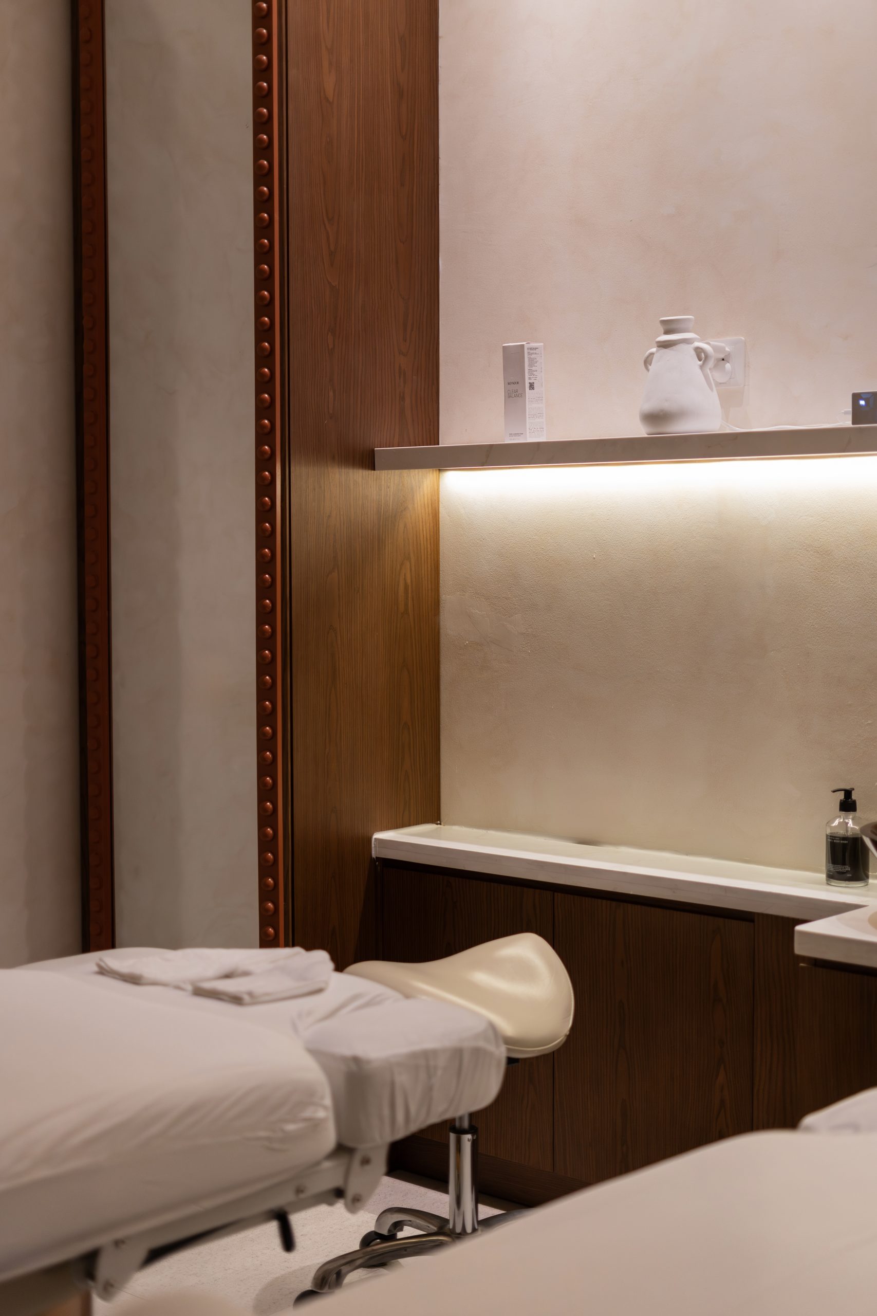 Treatment room at Mello Spa Canggu with a facial stool, timber cabinetry and a lit product shelf